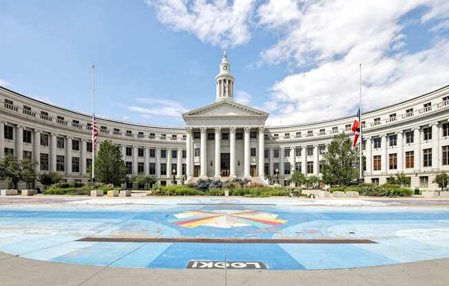 A large white building with a central dome and a rainbow mosaic in front.