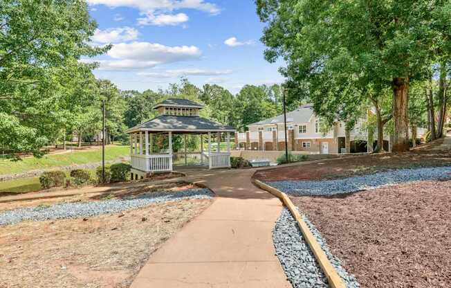 A gazebo is surrounded by a gravel garden and a paved walkway.