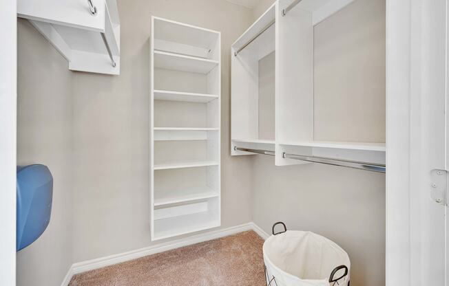 a laundry room with white cabinets and a trash can