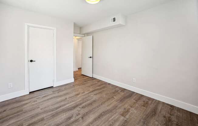 an empty room with white walls and wood flooring