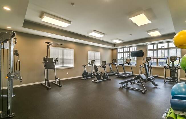 a large fitness room with exercise equipment and windows