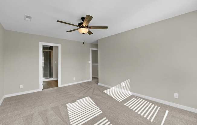 an empty living room with a ceiling fan and shadows on the floor