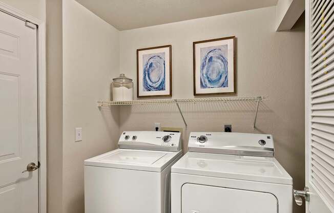 an empty laundry room with two white washers and dryers