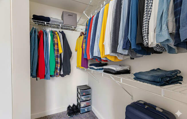 A closet full of clothes and a suitcase on the floor.