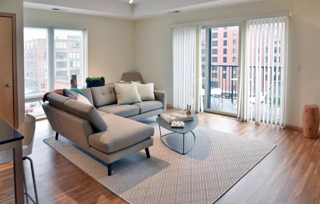 A living room with a grey couch and a glass table.