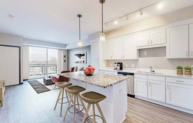 A kitchen with white cabinets and a marble countertop.