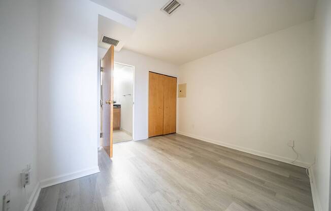 A room with a wooden floor and a door leading to another room.