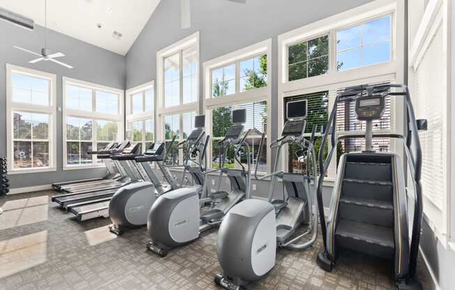 a gym with cardio equipment and windows