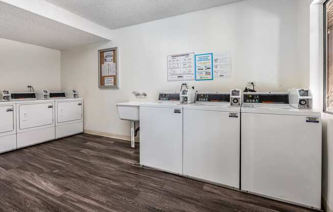 a kitchen with white appliances and a wood floor and white walls