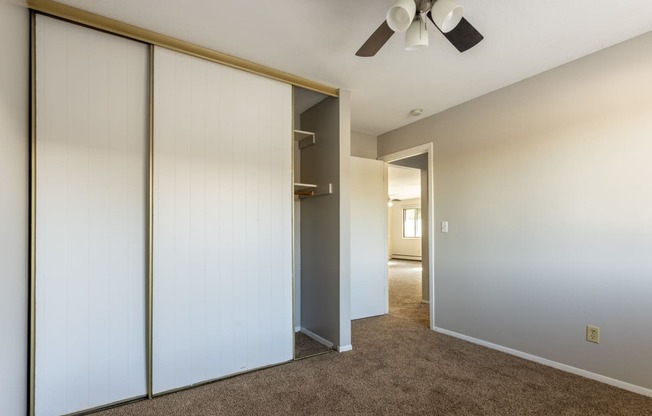 an empty bedroom with a closet and a ceiling fan