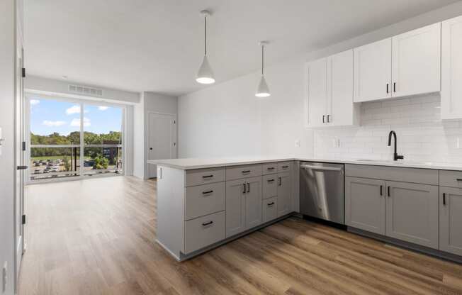 an open kitchen and living room with white cabinets and a sliding glass door