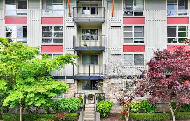 A building with a balcony and a small garden in front.