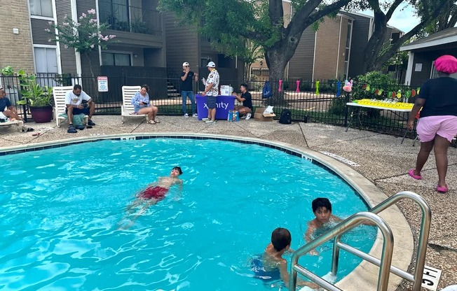 People are swimming in a pool with a blue tarp in the background.