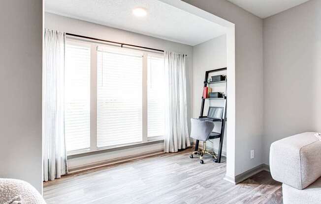 A room with a window, a chair, and a desk.