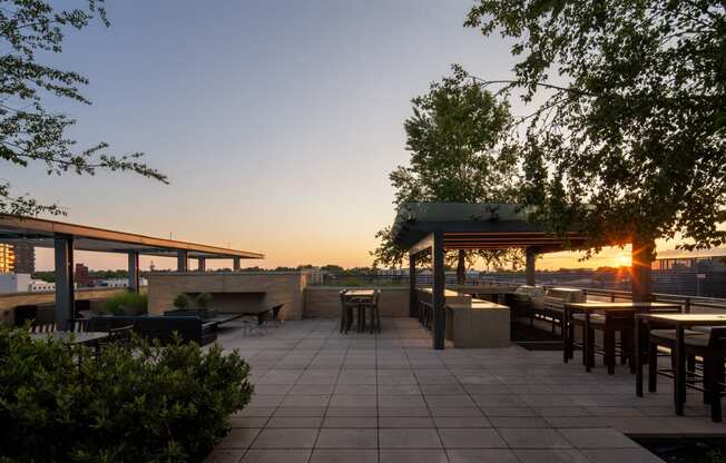 a rooftop patio with a firepit and a view of the city at sunset