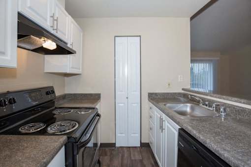 A kitchen with a black stove top oven and white cabinets.