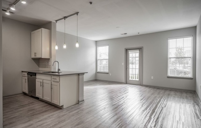 the living room and kitchen in a new home with white walls and wood floors