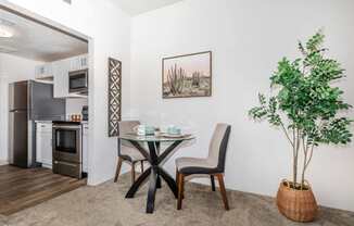 A dining area with a table and chairs and a potted plant.