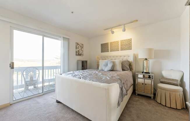 a bedroom with a bed and a sliding glass door to a balcony