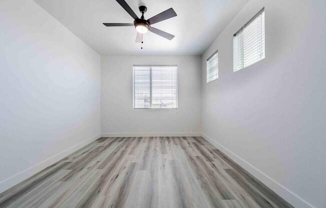an empty room with wood floors and a ceiling fan