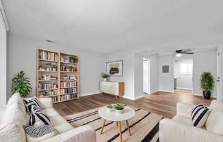 A living room with a white couch, a coffee table, and a bookshelf.