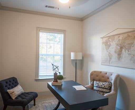 A compact home office with a modern desk, upholstered chairs, and a world map on the wall.