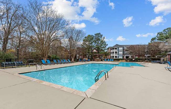 A large swimming pool surrounded by trees and chairs.