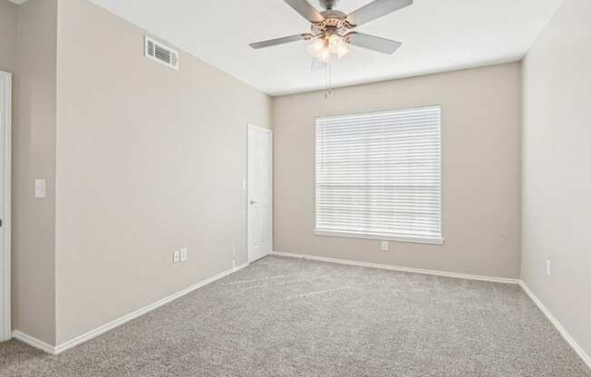 an empty room with a ceiling fan and a window