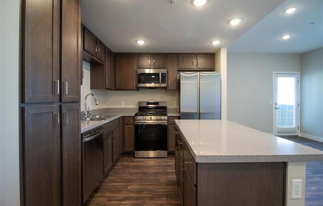 a kitchen with wooden cabinets and a white counter top at Loma Villas Apartments, San Bernardino, 92408