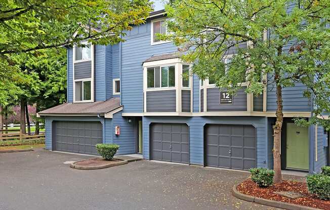 a blue house with two garage doors and trees