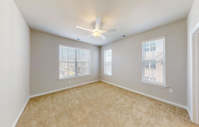 a bedroom with windows, carpet and a ceiling fan