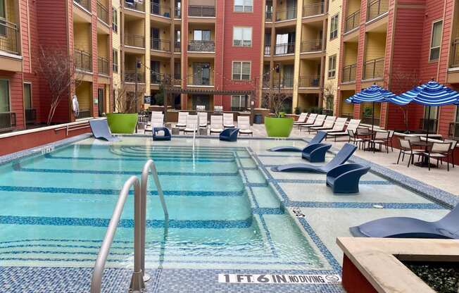 a swimming pool at an apartment building with chairs and umbrellas