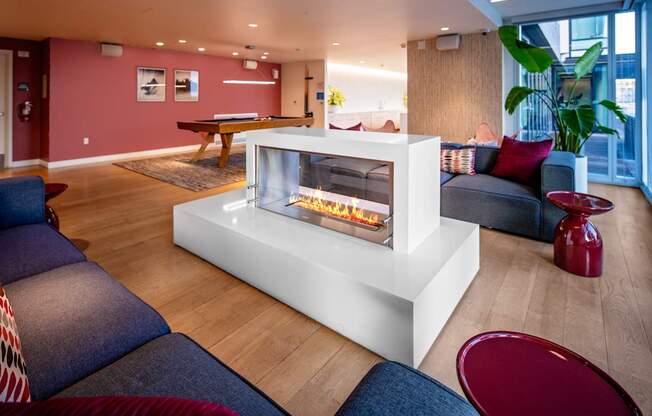 A modern living room with a white fireplace and blue couches.