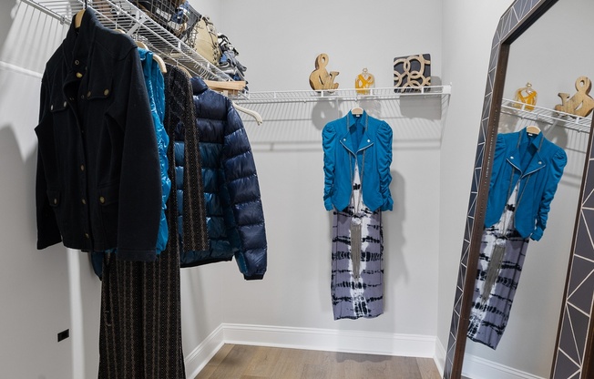 A row of coats are hanging on a rack in a room.
