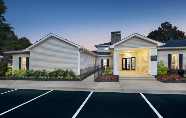 the exterior of a white building with a driveway and parking lot
