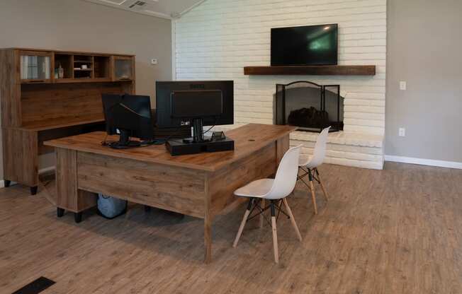 a home office with a wooden desk and two televisions