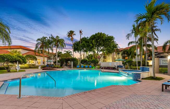 A swimming pool surrounded by palm trees and a bench.