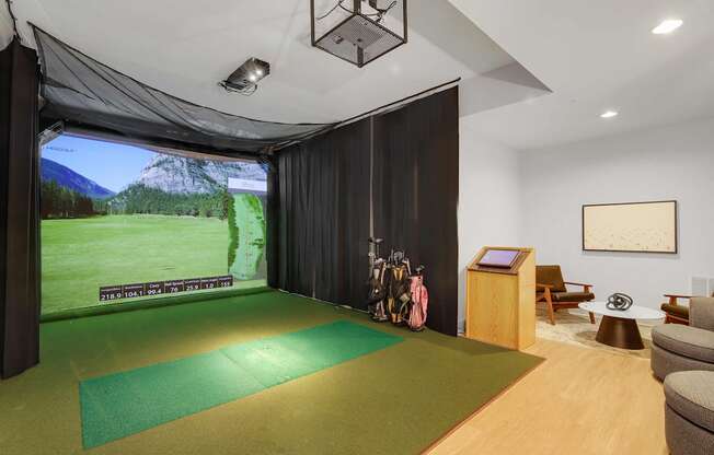 A room with a green mat on the floor and a screen on the wall.