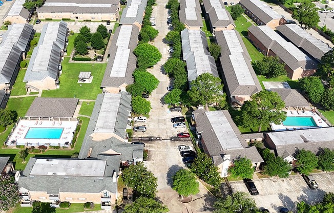 A bird's eye view of a residential complex with multiple houses and swimming pools.