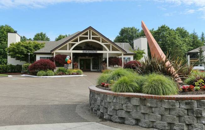 the front of a building with a fountain and plants