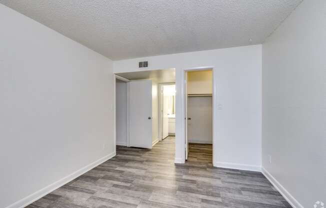 the living room of an apartment with white walls and wood flooring