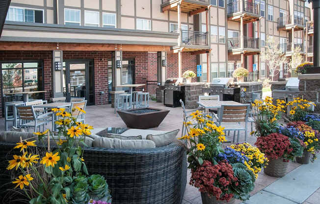 A patio with a table surrounded by chairs and potted plants.