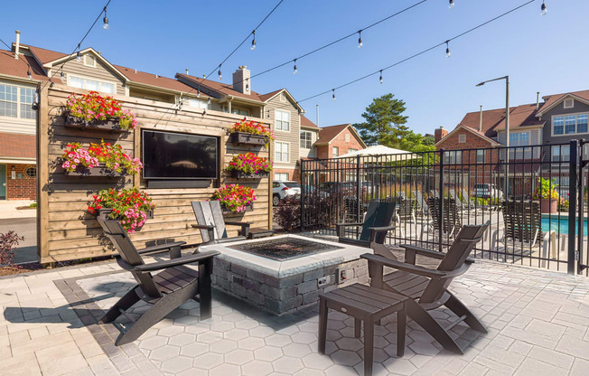 a patio with a fire pit and chairs and a fence