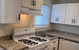 a kitchen with white cabinets and a stove and a sink