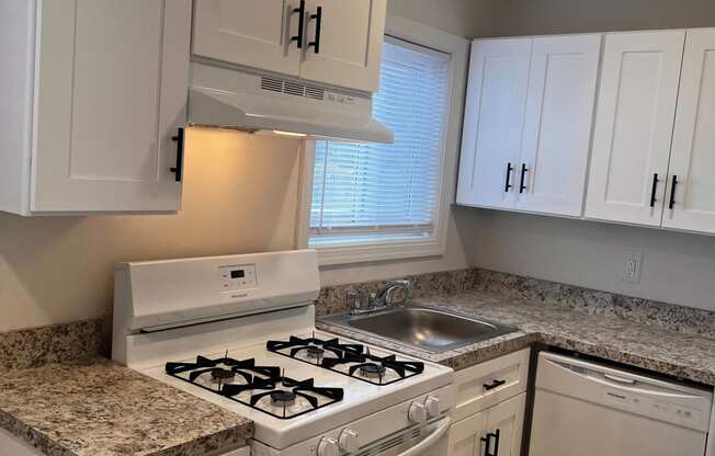 a kitchen with white cabinets and a stove and a sink