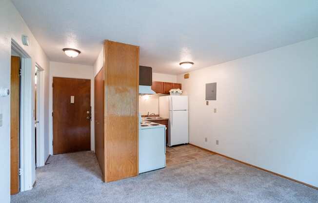 an empty living room with a kitchen with a refrigerator and a sink. Fargo, ND Morningside Apartments