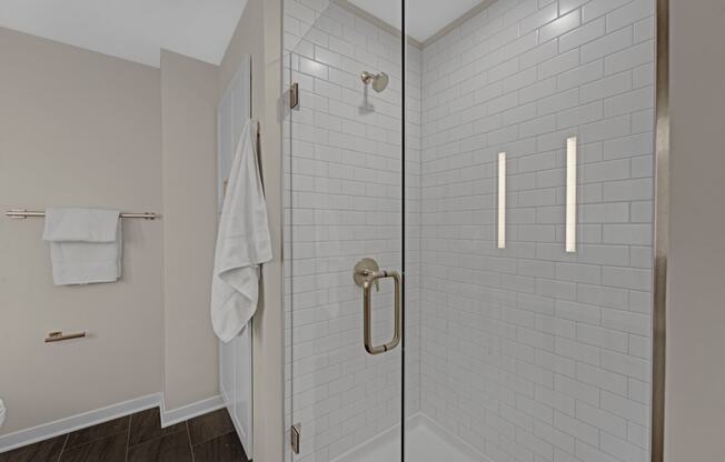a white tiled bathroom with a shower and a white towel