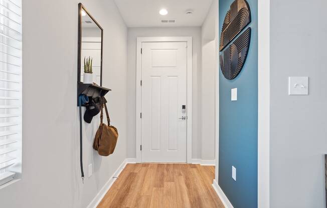 an entrance hall with overhead light, wood-style flooring, and a blue accent wall in a home at Sanctuary at Indian Creek