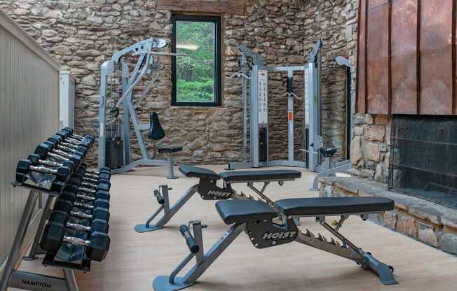 A home gym with a variety of equipment including a bench, dumbbells, and a cable machine. at Mill House at East Cobb, Georgia