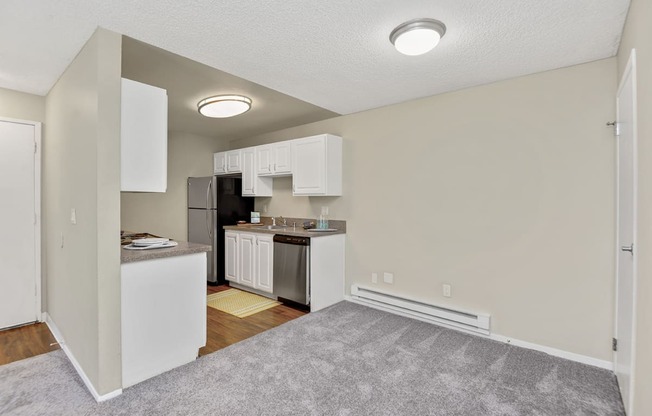 a living room with a kitchen in the background and a carpeted floor in the foreground